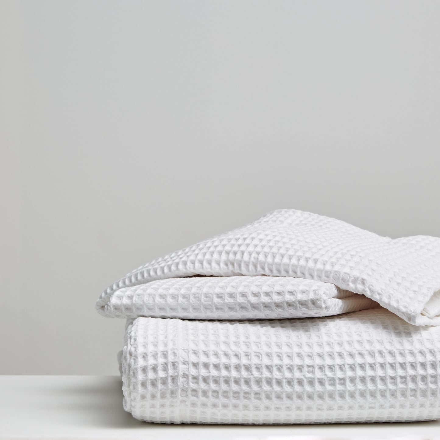 Stack of white textured blankets on a light gray background