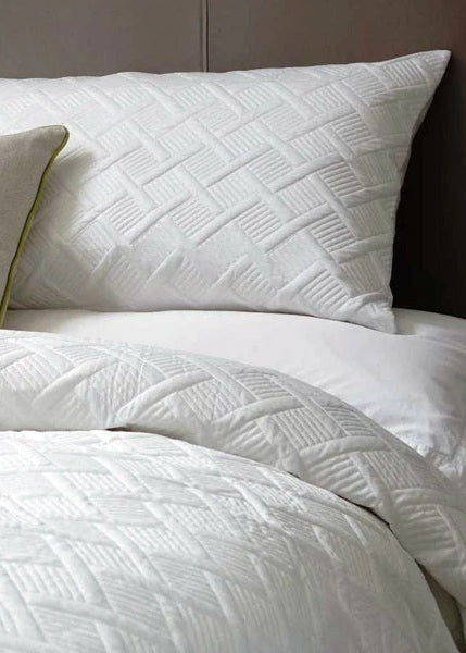 White textured bedding set on a bed with a dark headboard.