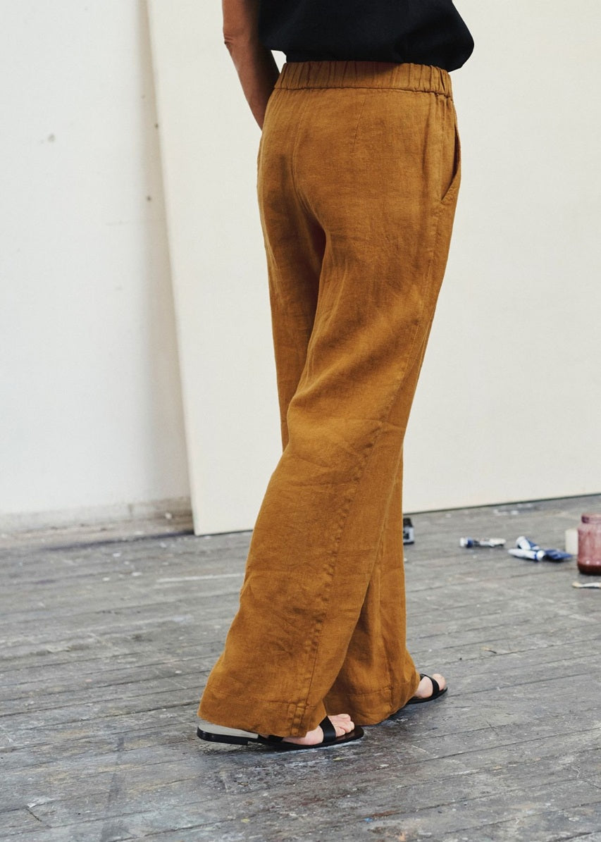 Person wearing mustard yellow wide-leg pants on a wooden floor.