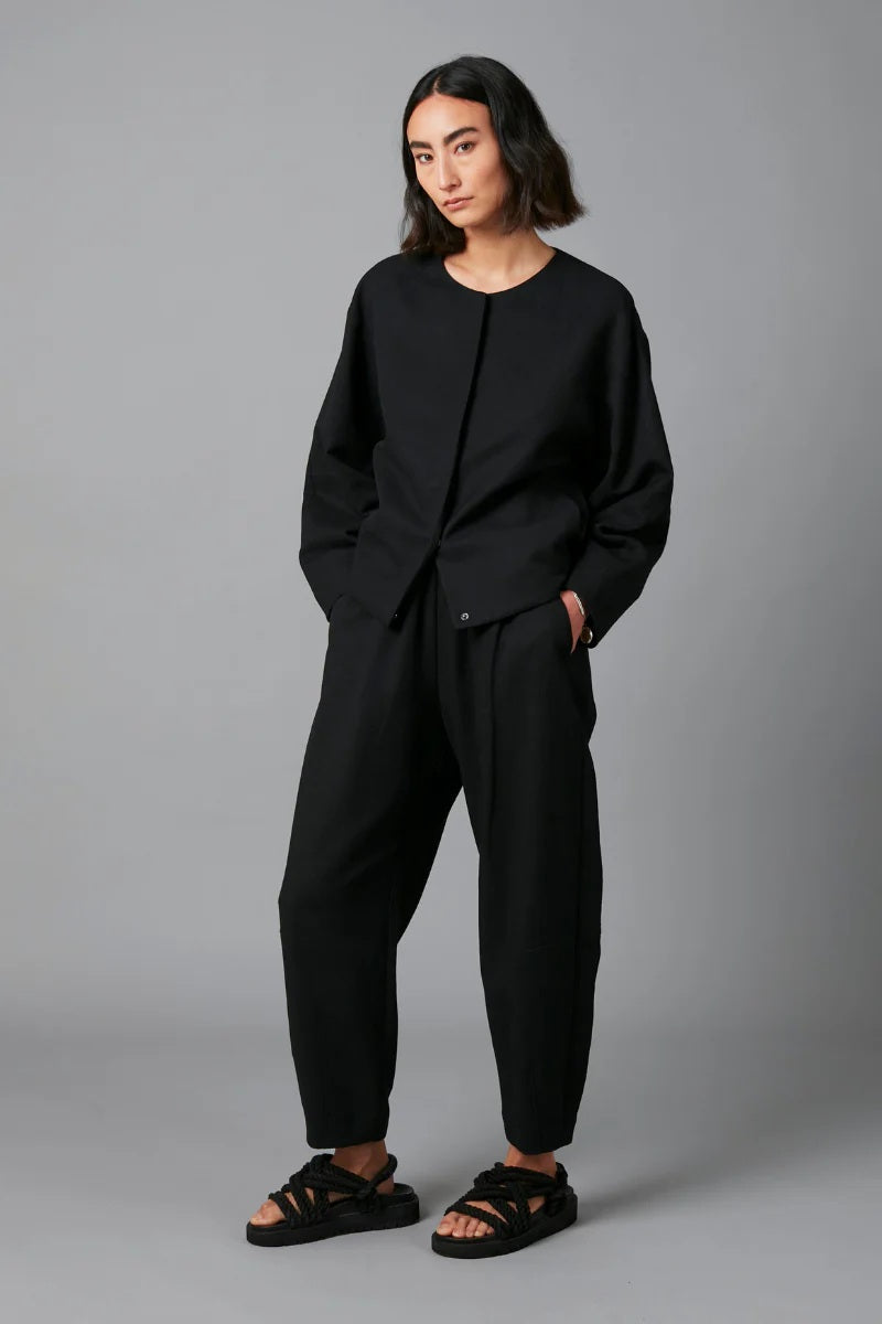 Person wearing a black outfit on a gray background