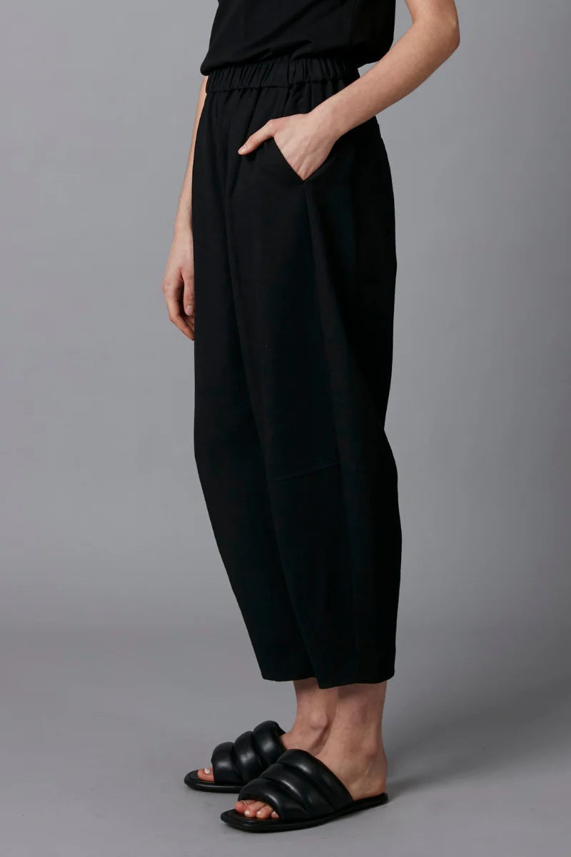 Person wearing black pants and sandals on a gray background
