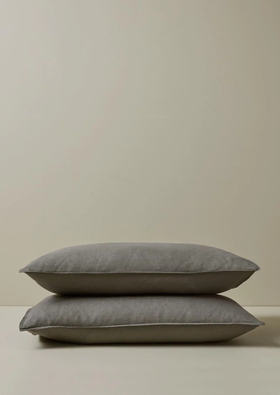 A pair of gray linen pillowcases with a flanged edge, displayed on a neutral background.