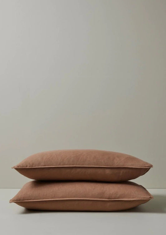 A pair of beige linen pillowcases with a flanged edge, stacked on top of each other.