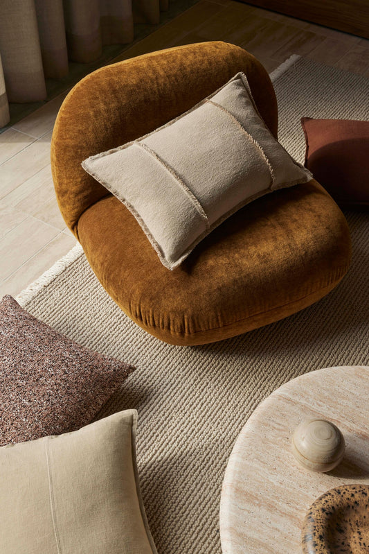Round brown cushion with a beige pillow on a light wooden floor.