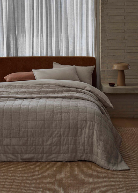 Bedroom with a bed covered in a textured gray comforter, pillows, and a wooden headboard.