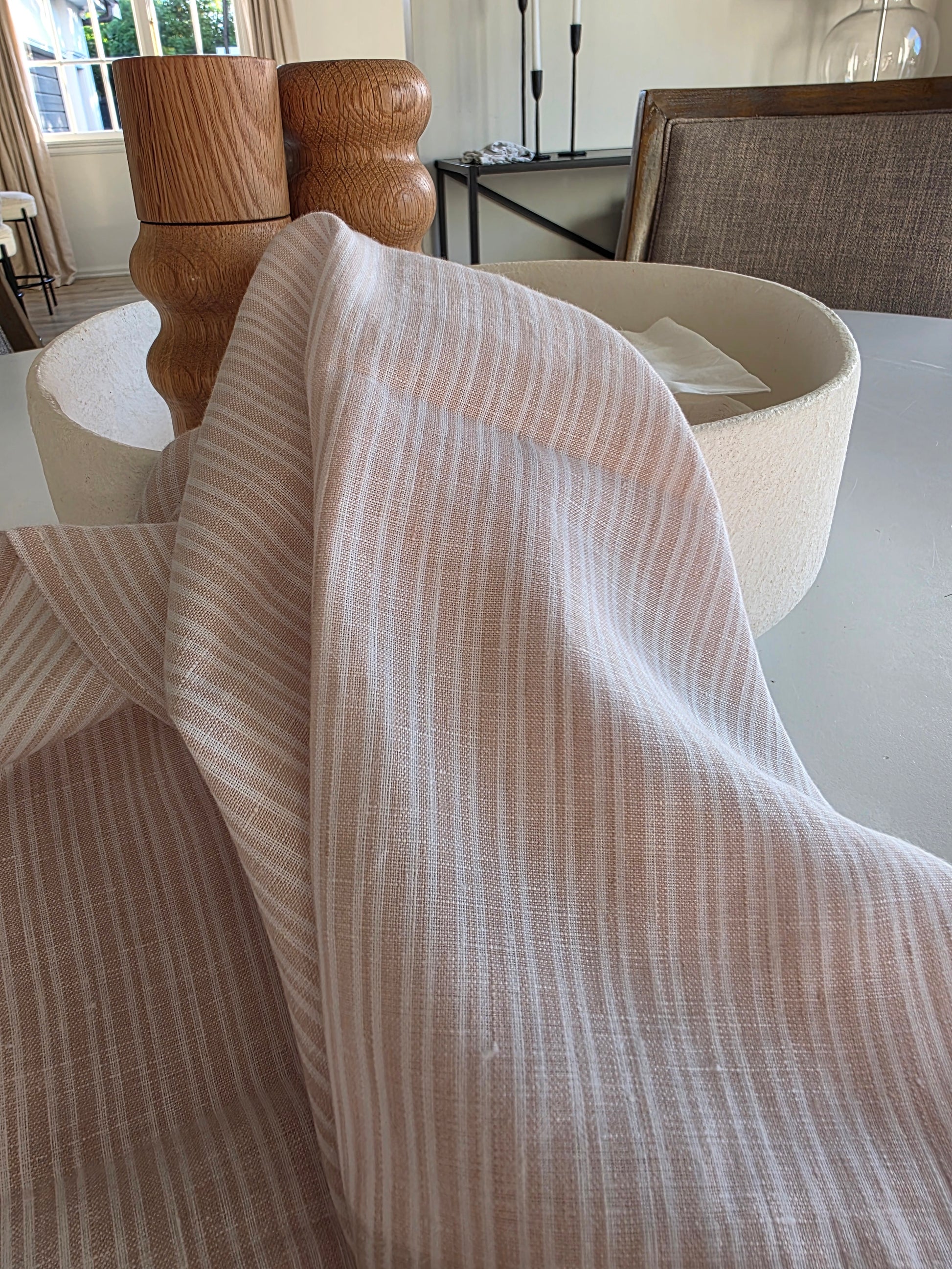 Close-up of a beige textured fabric draped over a wooden chair.