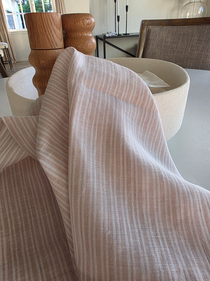 Close-up of a beige textured fabric draped over a wooden chair.