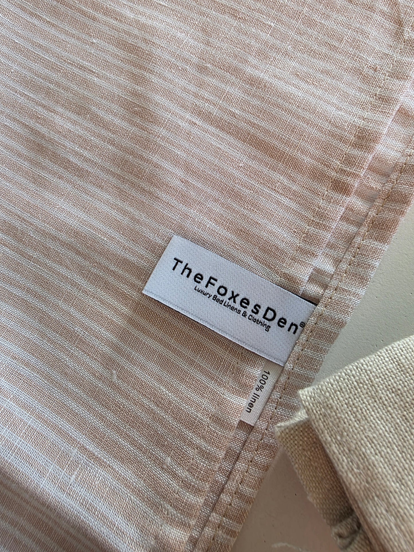 Fabric with 'The Foxes Den' label on a textured beige background