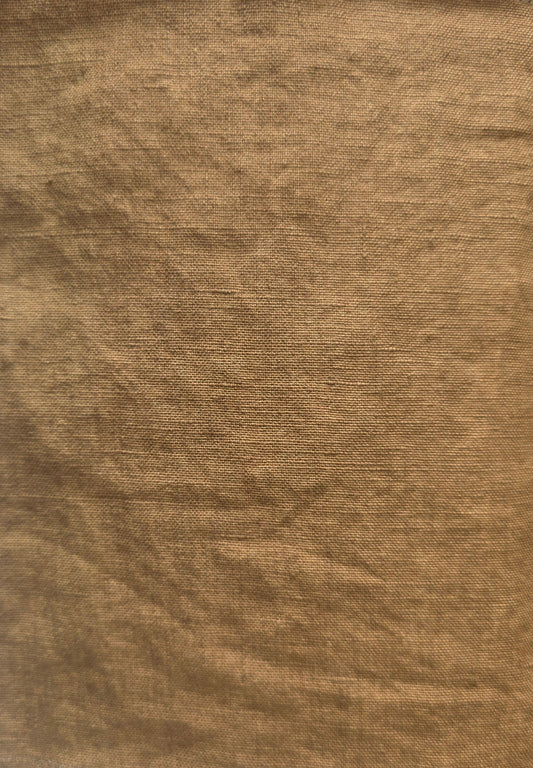 A square piece of textured tan fabric with frayed edges, laid flat on a white surface.