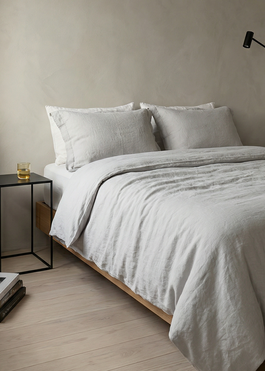 Minimalist bedroom with a bed, nightstand, and lamp against a plain wall.