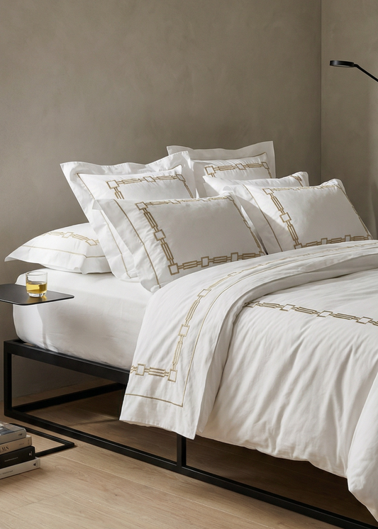 Neatly made bed with white bedding in a bedroom setting.