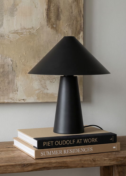 Black table lamp on a stack of books with a textured wall in the background