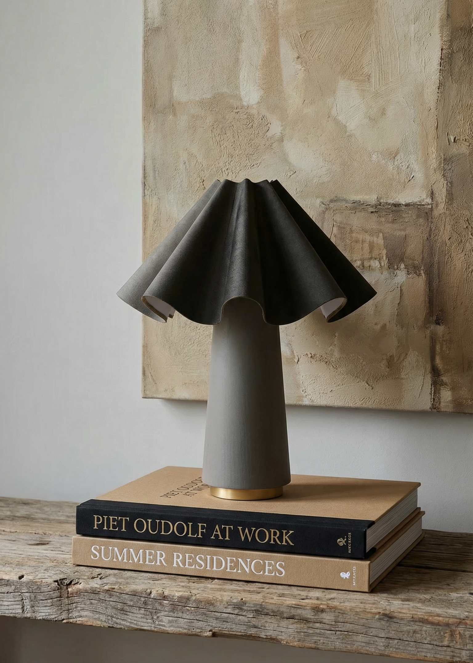 Dark gray table lamp on a stack of books with a textured wall in the background
