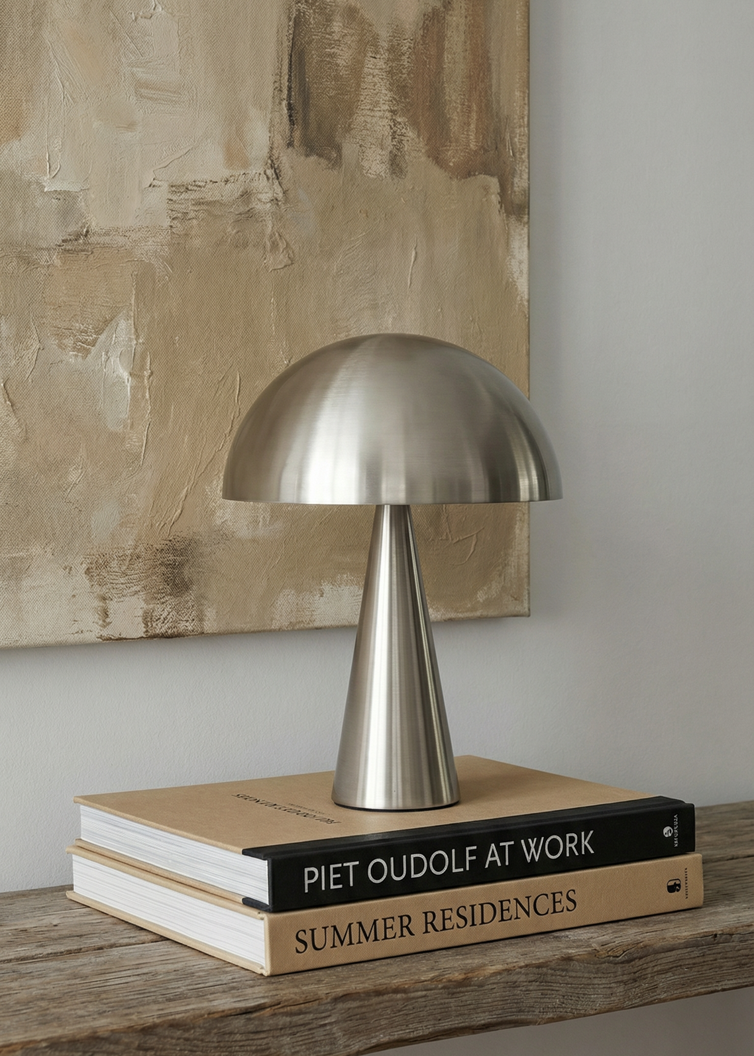 Metallic table lamp on a stack of books with a textured wall in the background