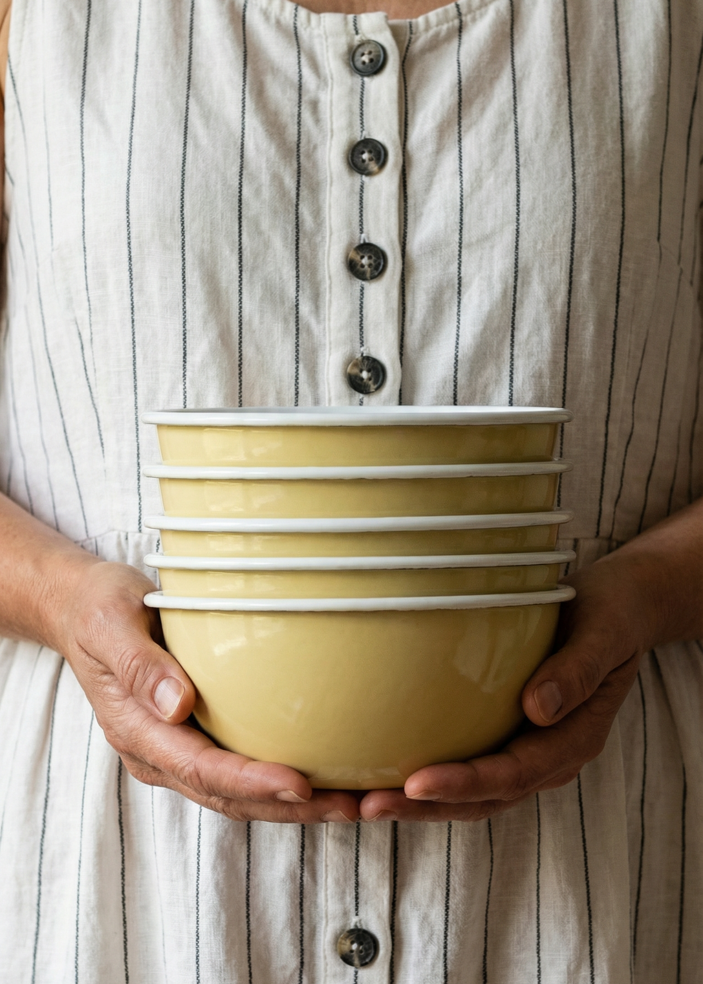Person holding a yellow ceramic bowl with a striped dress