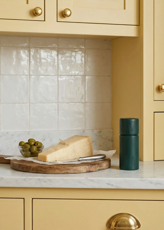 Yellow kitchen with marble countertop, cheese, and green bottle.