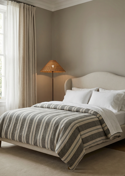 Neatly made bed with striped bedding in a bedroom setting.