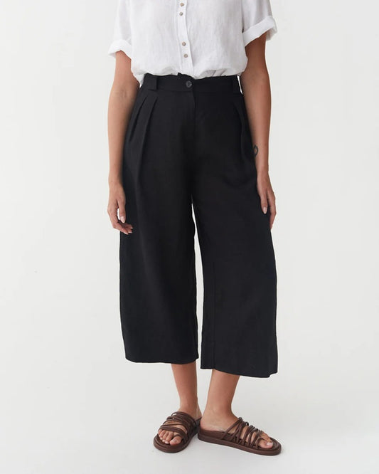 Person wearing black wide-leg pants and a white shirt on a white background