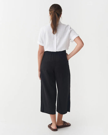 Person wearing a white shirt and black pants on a white background