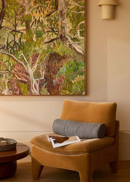 Living room with a mustard chair, round table, and large forest painting on the wall.