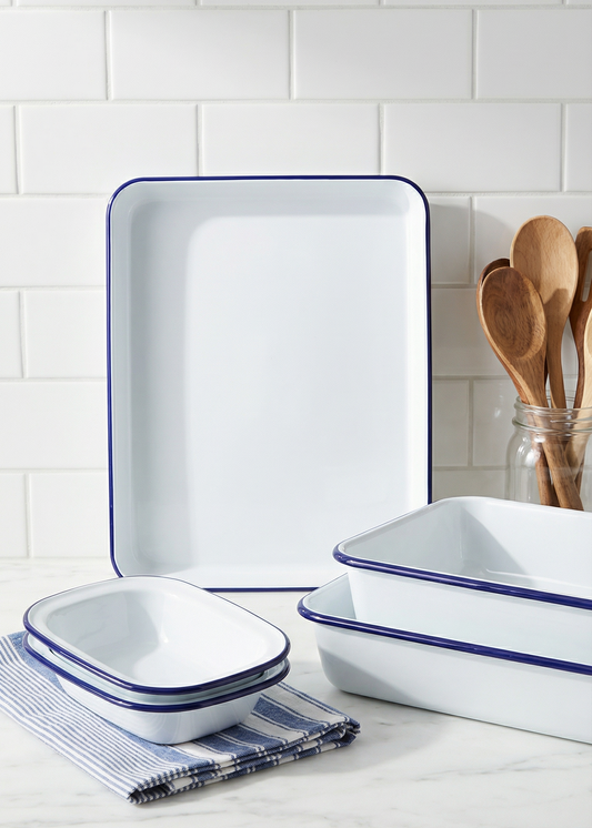 Set of white enameled cookware with blue rims on a kitchen counter.