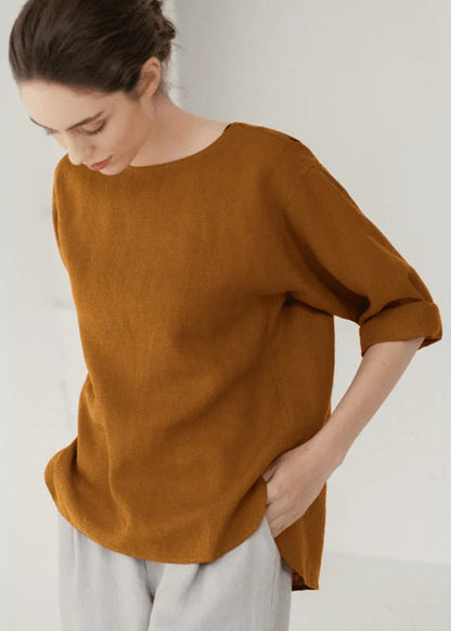 Woman wearing a brown top and white pants against a plain background