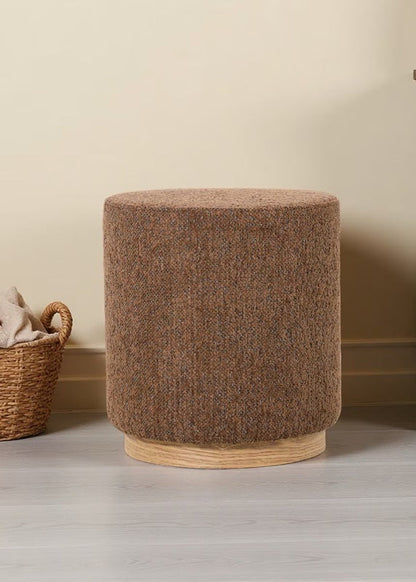 Brown textured ottoman next to a wooden cabinet with wicker doors in a room.