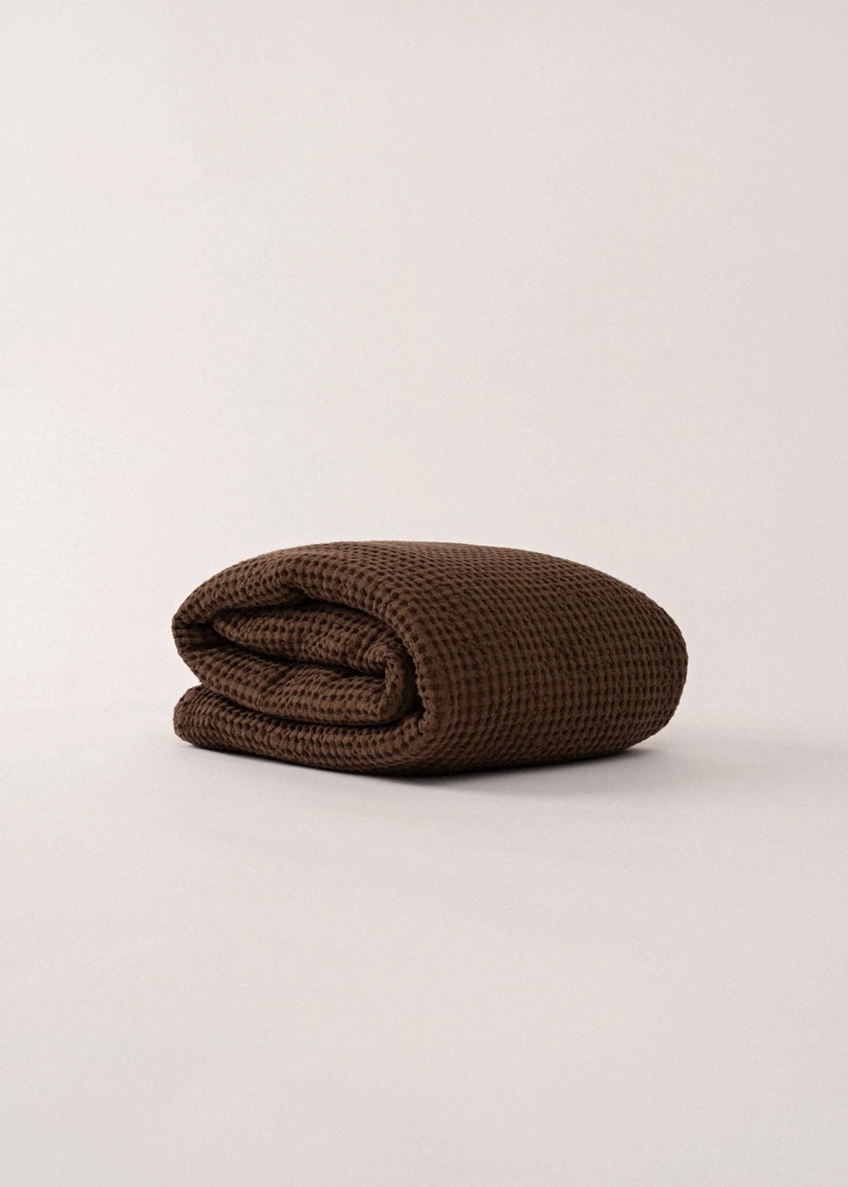 Folded brown blanket on a light beige background