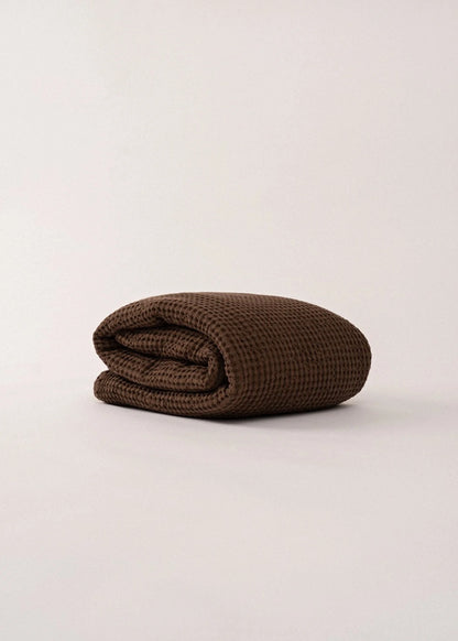 Folded brown blanket on a light beige background