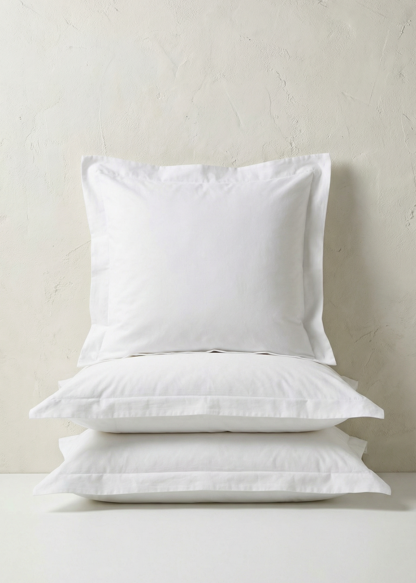 Two white pillows stacked on a light gray surface with a neutral background