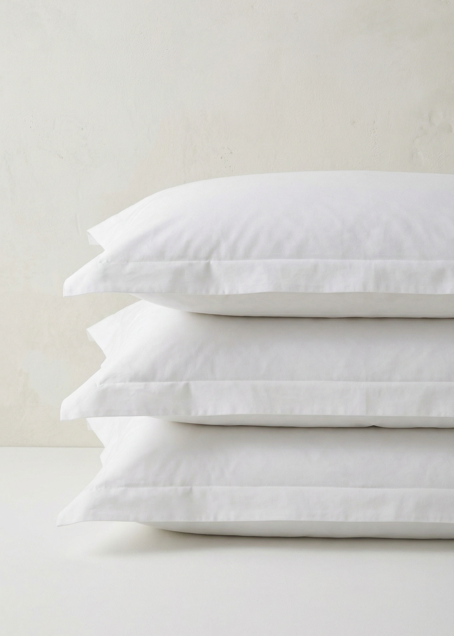 Stack of white pillows on a light gray background