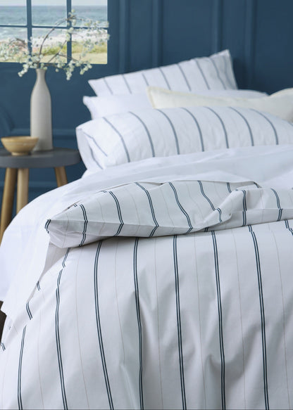 Striped bedding set on a bed with a window view of water and sky.