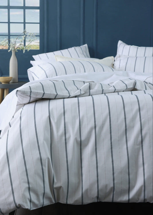 Striped bedding set on a bed with a blue wall and window in the background