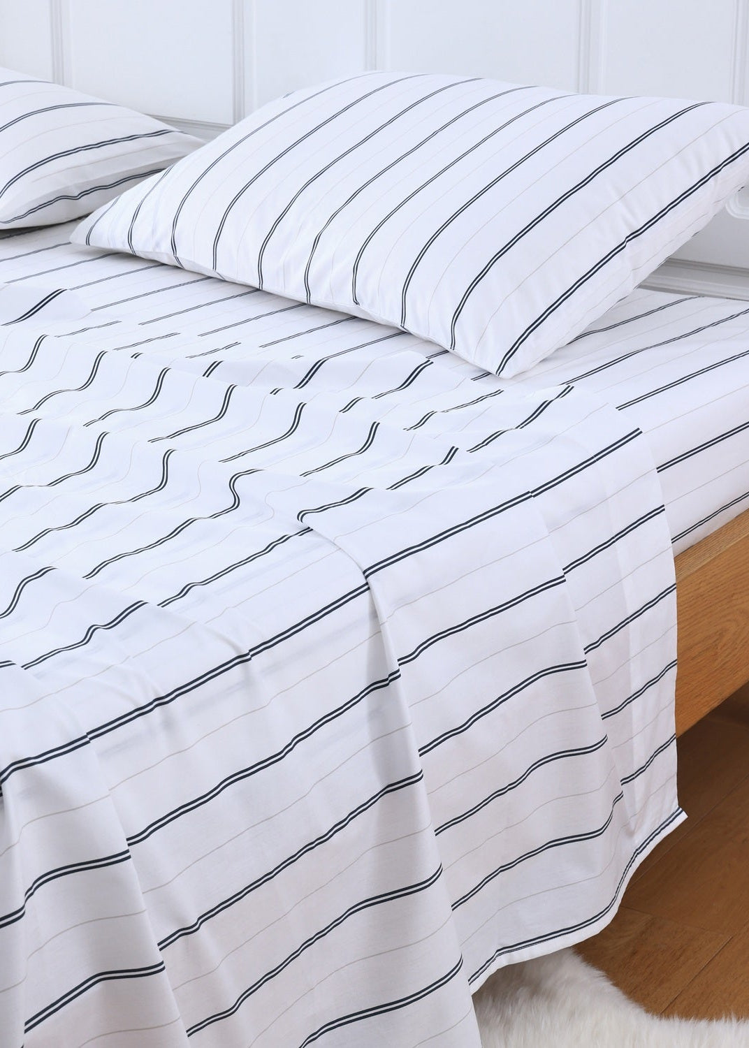 Bed with white bedding featuring black wavy lines and a wooden headboard.