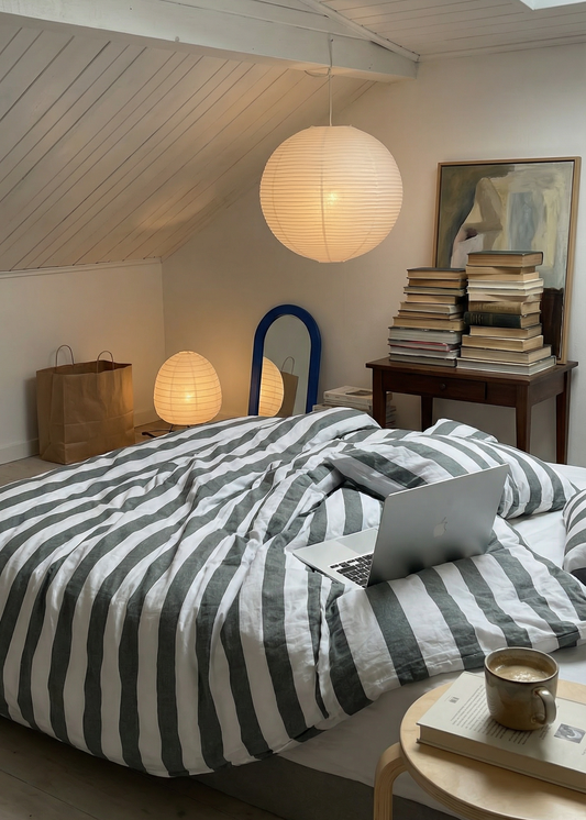 Bedroom with striped bedding, books, and a laptop on a bed.