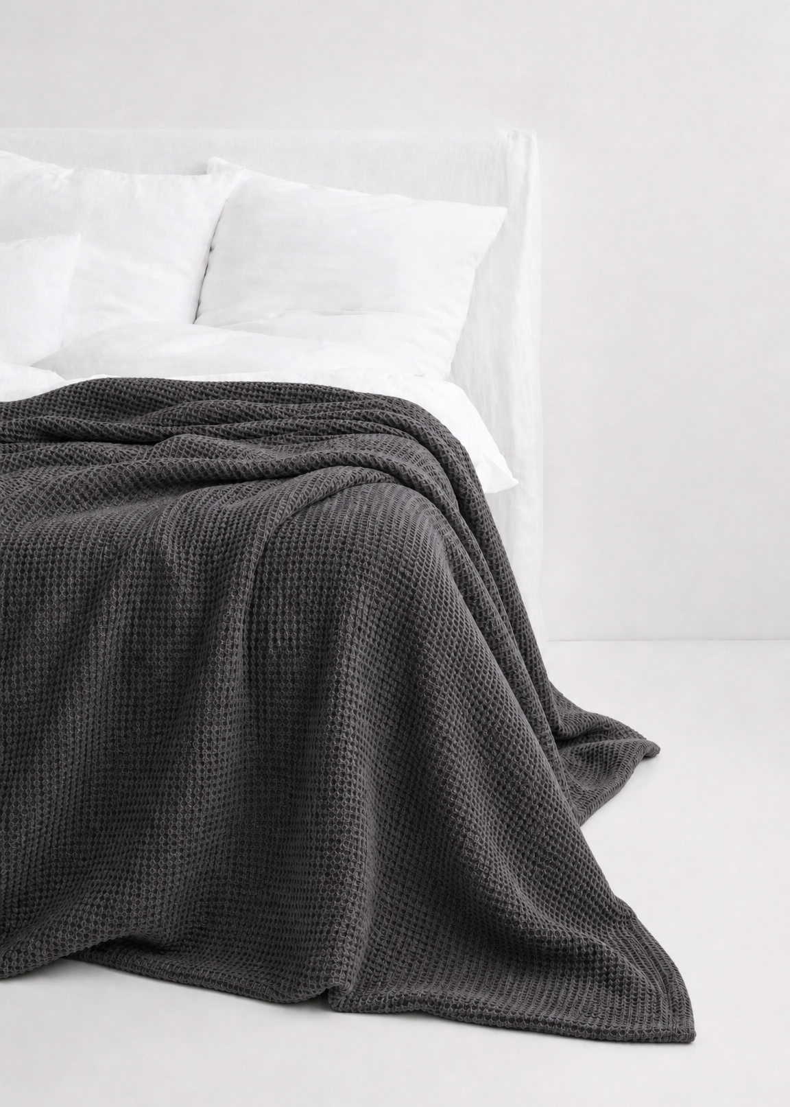 Gray textured blanket on a white bed with white pillows