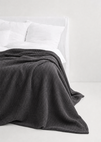 Gray textured blanket on a white bed with white pillows