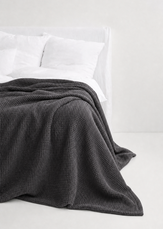 Gray textured blanket on a white bed with white pillows