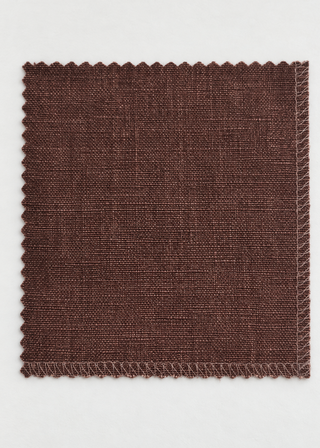 A square fabric swatch with scalloped edges in a dark brown woven material, displayed flat against a light gray background.