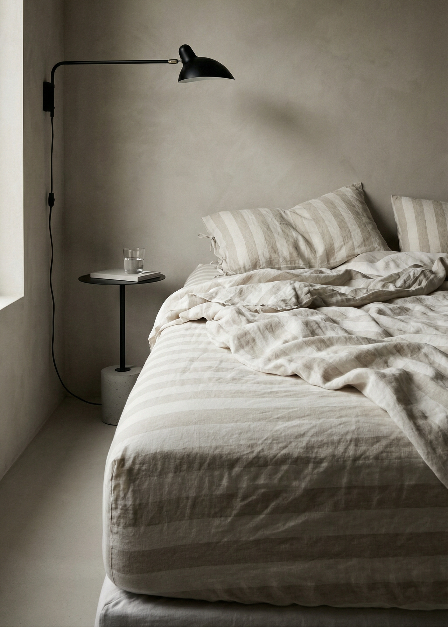 Minimalist bedroom with a bed, lamp, and small table.