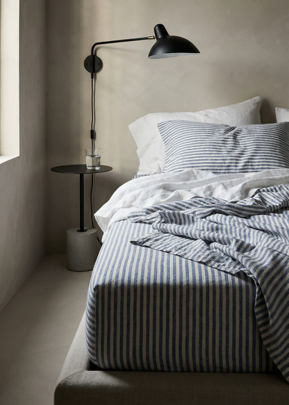 Bedroom with striped bedding and a lamp on a side table.