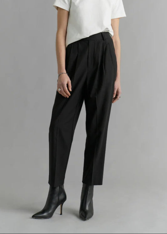 Woman wearing a white top and black pants on a gray background