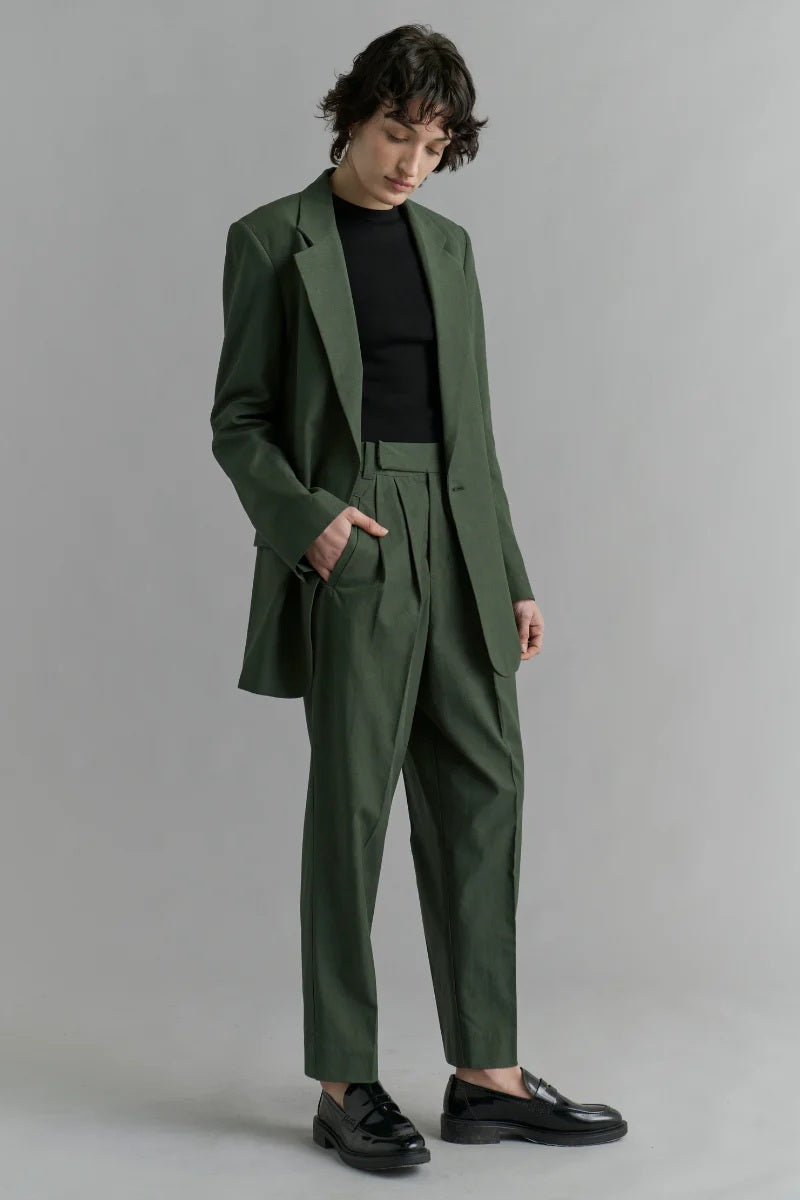 Person wearing a green suit with a black shirt against a gray background