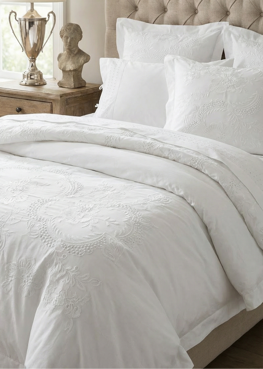 Neatly made bed with white bedding and a beige tufted headboard.