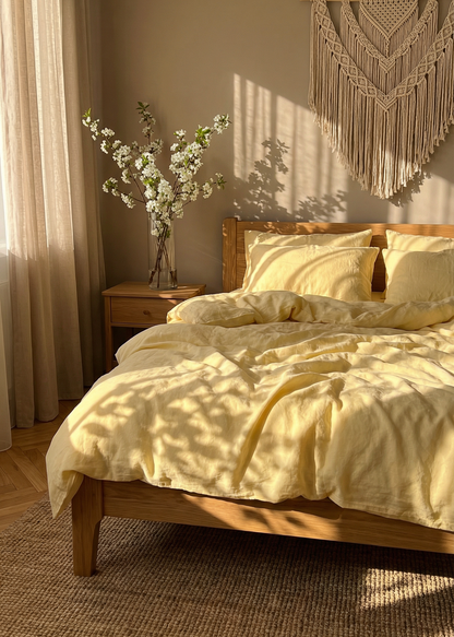 Bedroom with wooden bed, yellow bedding, and macrame wall hanging.