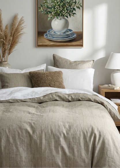Bedroom with a bed, pillows, and a framed picture of a vase with flowers on the wall.