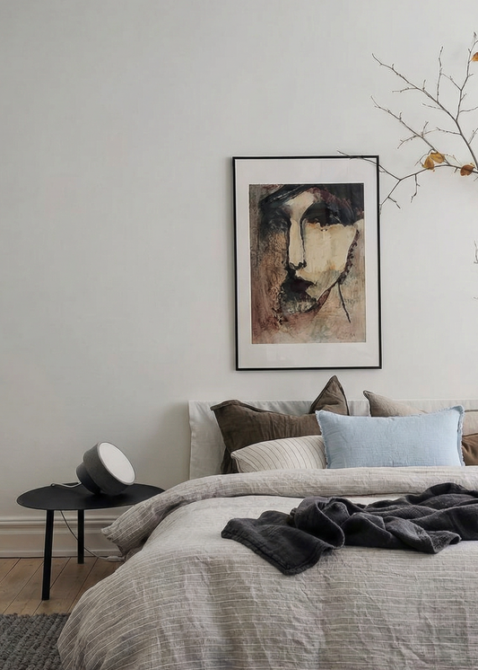 Cozy bedroom with a bed, pillows, and a painting on the wall.