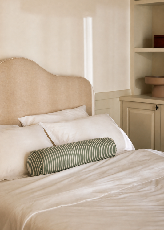 Beige bed with striped green pillow in a bedroom setting