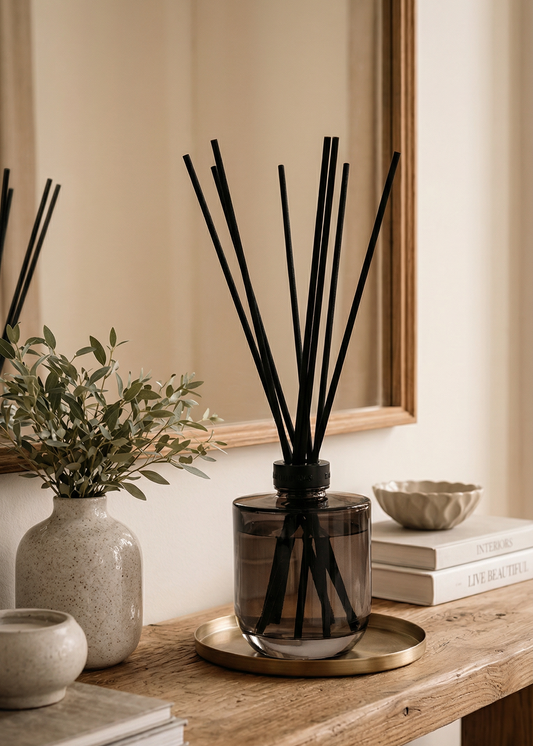 A diffuser with black sticks on a wooden table with decorative items.