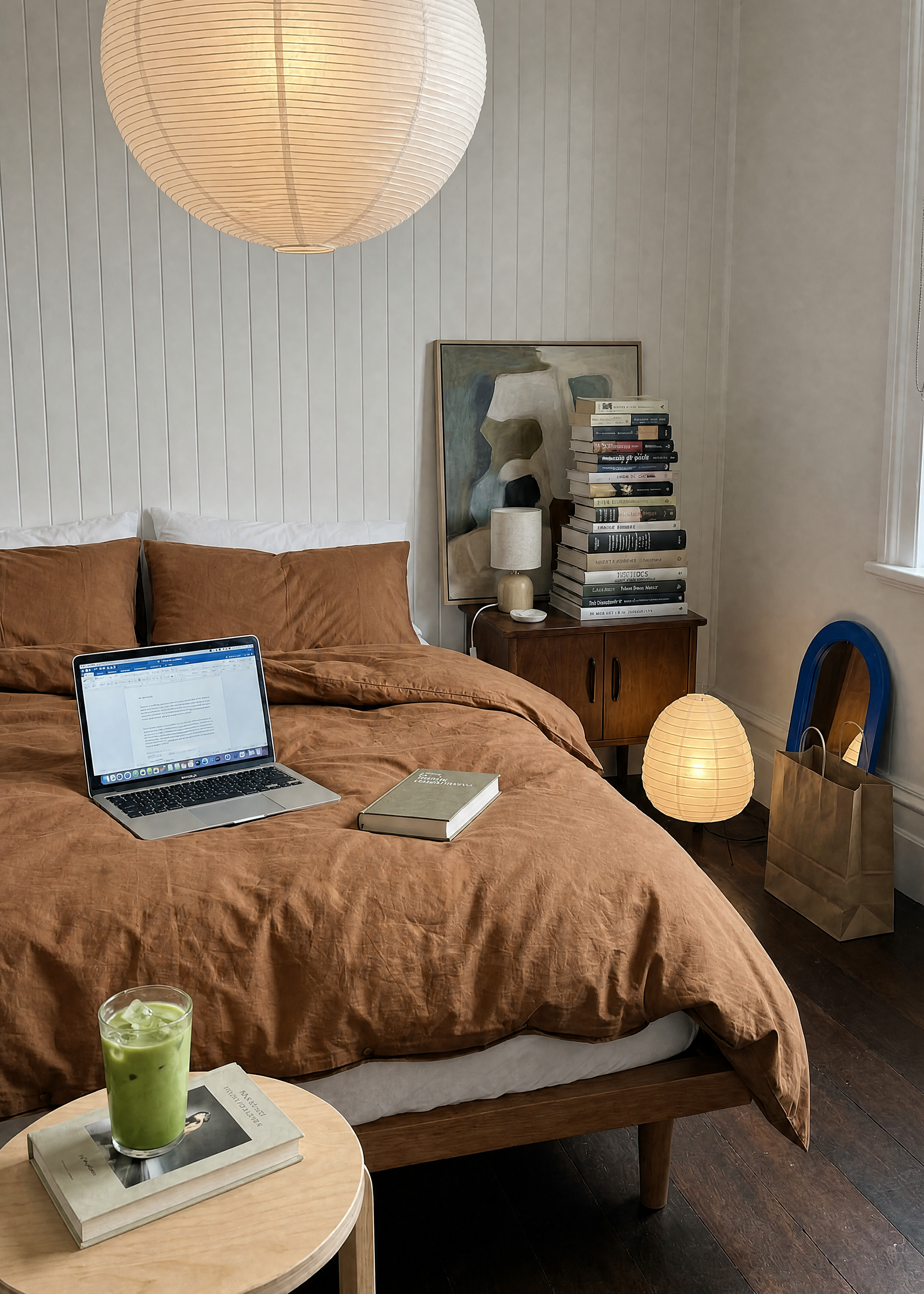 Modern bedroom with brown bedding, laptop, and books on a wooden nightstand.